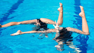 Graceful Upside-down Half Split Performance In Artistic Swimming Wallpaper