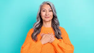 Grateful Middle Aged Woman Orange Sweater Wallpaper