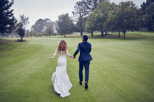Groom And Bride Running On Golf Course Wallpaper