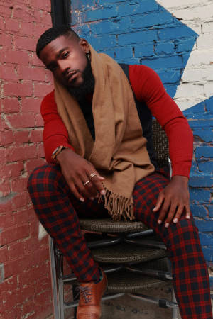 Handsome Black Man In Checkered Pants Posing With Confidence Wallpaper