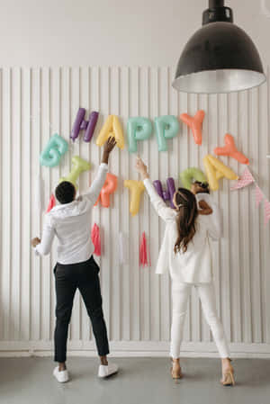 Happy Birthday Party - A Couple Of People In White Standing In Front Of A Happy Birthday Banner Wallpaper