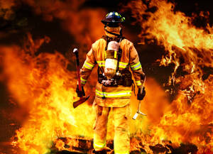 Heroic Fireman Braving A Monstrous Fire Wallpaper