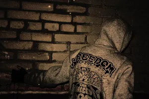 Hooded_ Figure_by_ Brick_ Wall Wallpaper