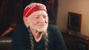 Iconic Singer Willie Nelson Posing With Braided Hair And Bandana Wallpaper