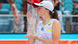 Iga Swiatek Triumphantly Kissing Her Glass Trophy Wallpaper