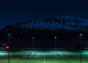 Illuminated Night Football Field Ready For The Game. Wallpaper