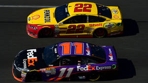 Intense Racing: Joey Logano And Denny Hamlin Battle On The Track Wallpaper