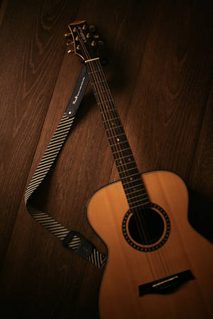 Intricately Crafted Acoustic Guitar With Striped Strap Wallpaper