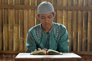 Islamic Boy Reading Quran Indoors Wallpaper