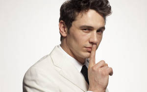 James Franco In White Suit Making A Silence Gesture Wallpaper