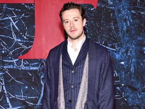 Joseph Quinn Posing On Wall Wallpaper