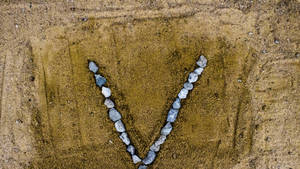 Letter V Shaped Rocks On Sand Wallpaper
