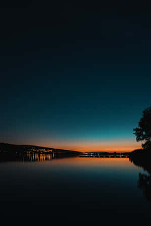 Lit Buildings Near Lake Under Starry Evening Sky Wallpaper