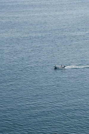 Lone Boat Sailing On The Ocean Wallpaper