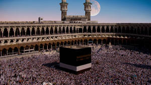 Majestic Kaaba Under The Gleaming Full Moon Wallpaper