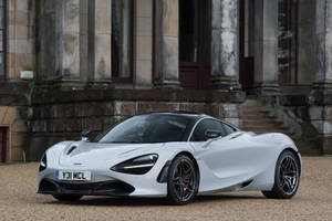 Majestic Mclaren 720s Parked Against Stone Building Wallpaper