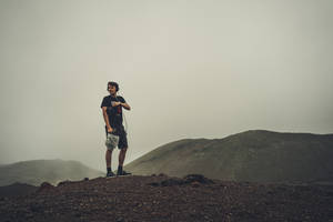Man In Black T-shirt And Brown Shorts Standing On Brown Rock Wallpaper