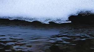 Melting Snow Edge Over Dark Water.jpg Wallpaper