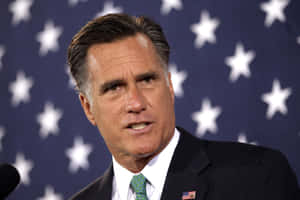 Mitt Romney Speakingwith Flag Background Wallpaper