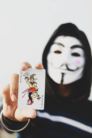 Mysterious Hacker Mask With Joker Card - A Symbol Of Cyber Rebellion Wallpaper