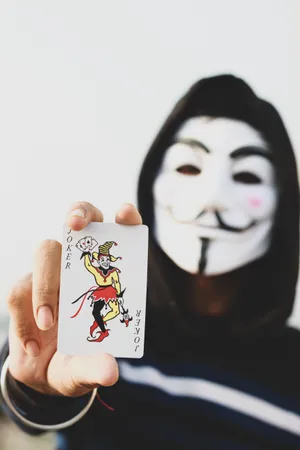 Mysterious Hacker Mask With Joker Card - A Symbol Of Cyber Rebellion Wallpaper