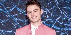 Noah Schnapp Against Blue Chain-like Graphic Wallpaper