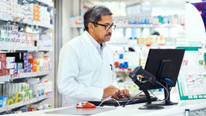 Old Pharmacist Checking Computer Wallpaper