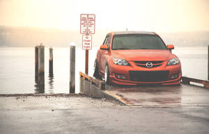 Orange Mazda 3 At Pier Wallpaper