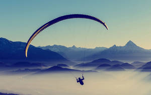 Paragliding Above Cloud-covered Mountains Wallpaper