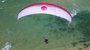 Paragliding Above Green Waters Wallpaper