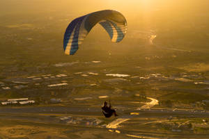 Paragliding Against Gleaming Sunset Wallpaper
