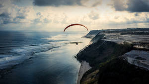Paragliding Near A Cliffside Beach Wallpaper