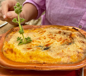 Person's Hand Garnishing A Baked Moussaka Wallpaper