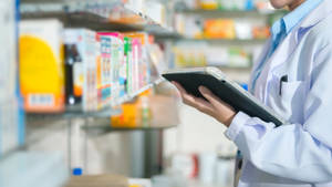 Pharmacist Holding Tablet Checking Medicines Wallpaper