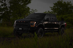 Powerful Ford Raptor With Vibrant Orange Headlights Shining In The Dark Wallpaper