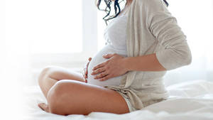 Pregnant Belly Massaging On White Bed Wallpaper