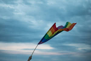 Pride Flag Waving Against Cloudy Sky Wallpaper