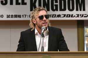 Pro Wrestler Kenny Omega Looking Dashing In A Suit And Sunglasses. Wallpaper