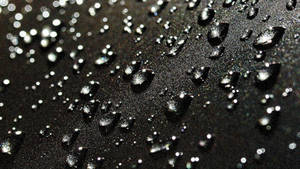 Raindrops Falling On A Deep Black Surface Wallpaper
