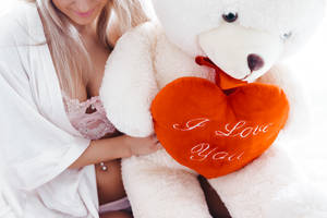 Red And White Teddy Bear Hugged By Woman Wallpaper