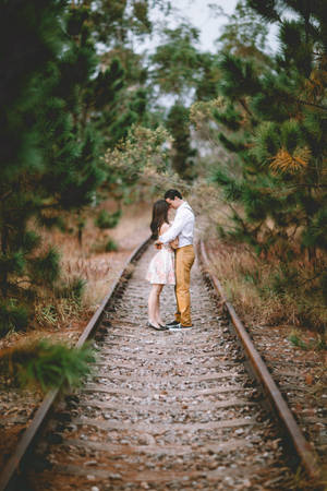 Romantic Couple Embrace On Train Tracks Wallpaper