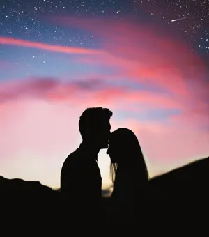 Romantic Couple Forehead Kiss Under Pink Skies Wallpaper