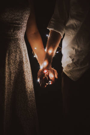 Romantic Couple Holding Hands With Fairy Lights Wallpaper
