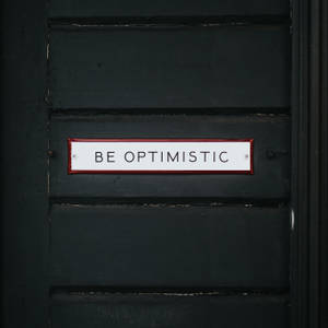 Shining Door Sign Displaying The Word Optimistic Wallpaper