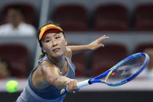 Shuai Peng Powerfully Reaching For A Tennis Ball In A Match Wallpaper