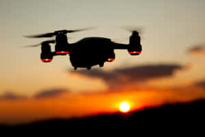 Silhouetted Drone Against Sunset Sky Wallpaper