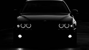 Sleek Black Bmw Car In Night City Scenery Wallpaper