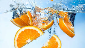 Sliced Orange Fruits Deep In Water Wallpaper