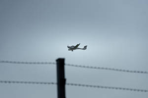 Small Plane In Gray Sky Wallpaper