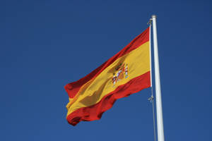 Spain's Pride - The Spanish Flag Majestically Flying Under Clear Blue Skies Wallpaper